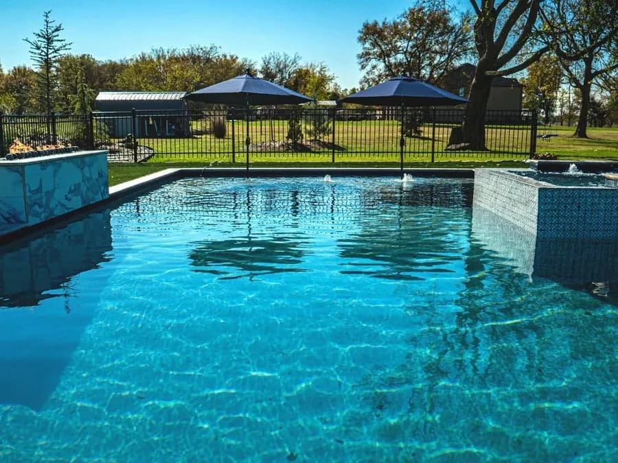 Raised spa spilling into a geometric pool by Anthem Pools