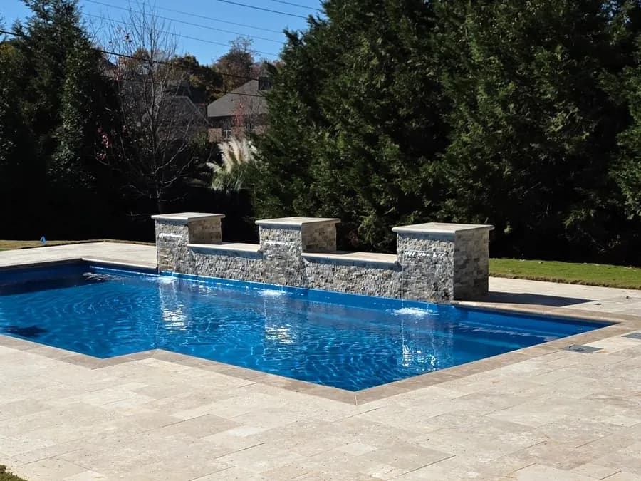 Stacked-stone water wall with sheer descents into a pool by Anthem Pools