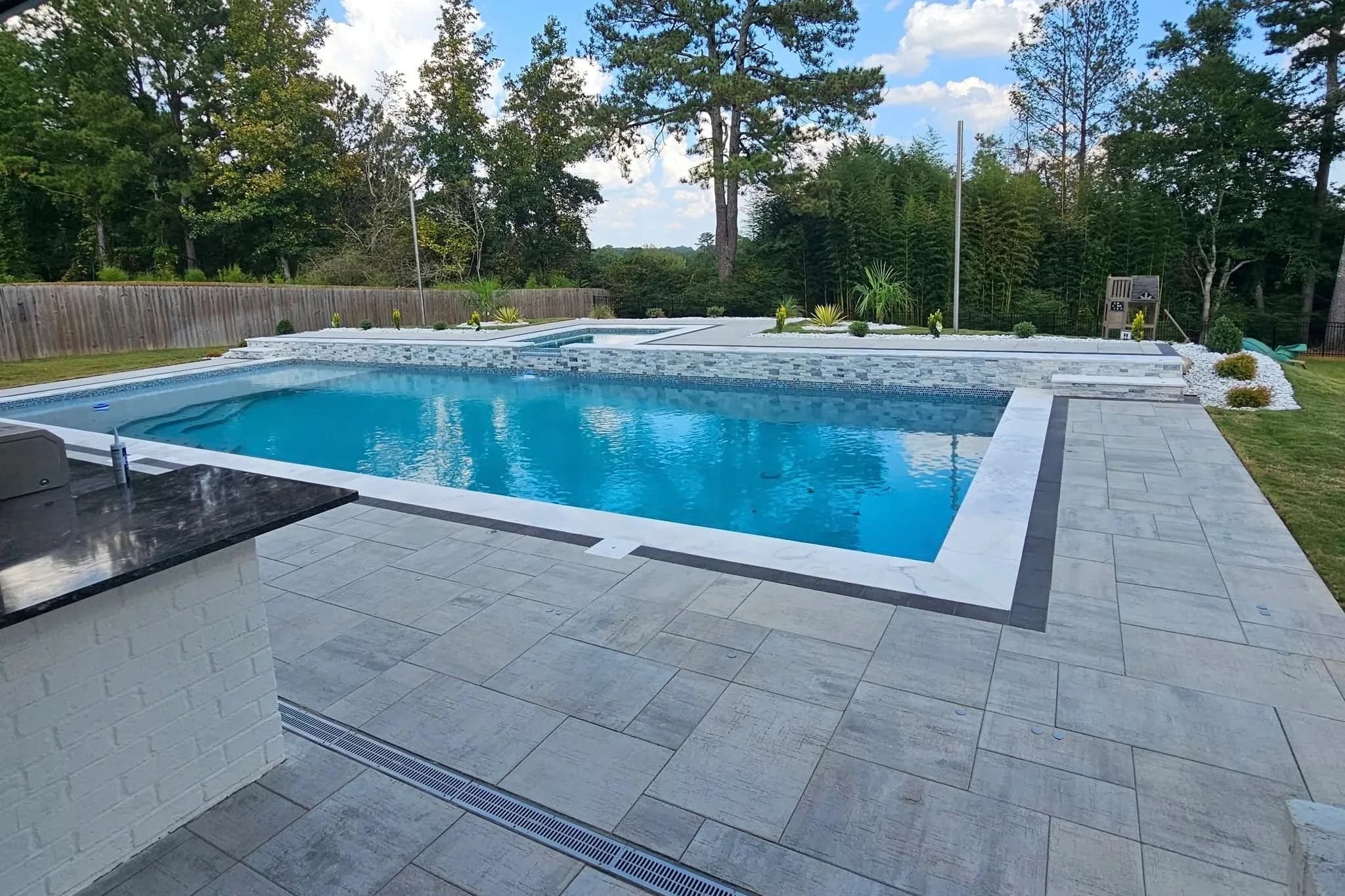 Modern rectangular gunite pool with an attached spa and paver deck, built by Anthem Pools