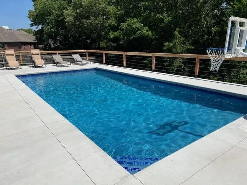 Rectangular gunite pool with a mosaic tile accent and wide concrete deck, built by Anthem Pools